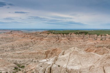 Yeşil alanın arka planındaki renkli tepeler ve kaya oluşumları, Badlands Ulusal Parkı, Güney Dakota, ABD 'de mavi bir gökyüzünün altında