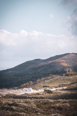 Dağlık arazilerin dikey görüntüsü ve ortasında küçük bir ev.