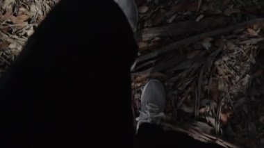 Güneşli bir günde ormanda yürüyen bir insanın ayak görüntüsü.