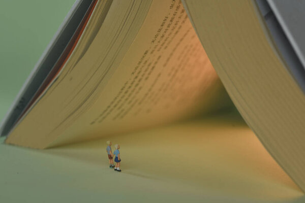 A closeup shot of a statuettes of children looking to the opened book - concept of knowledge