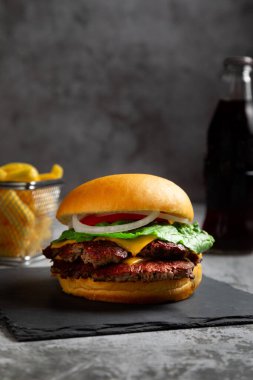 Masadaki lezzetli bir çizburgerin dikey yakın çekimi.