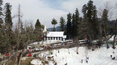 Ağaçlarla çevrili bir katedralin ve kısmen karla kaplı bir parkın yüksek açılı güzel bir görüntüsü..