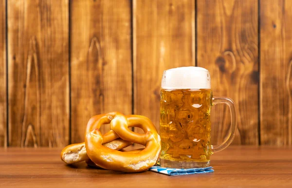 A closeup shot of pretzel and beer for German Oktoberfest on a brown table