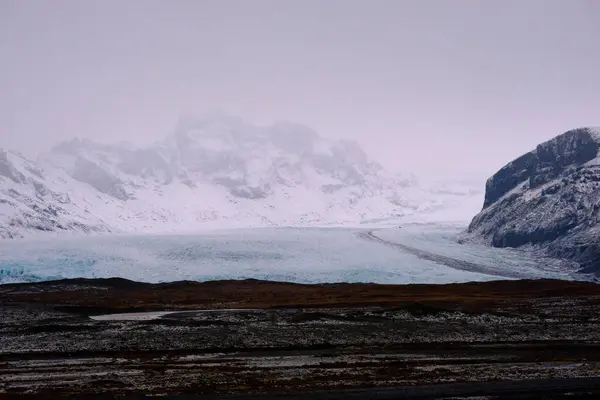 Blå Glaciär Mellan Två Berg Med Mörkbrun Förgrund — Stockfoto