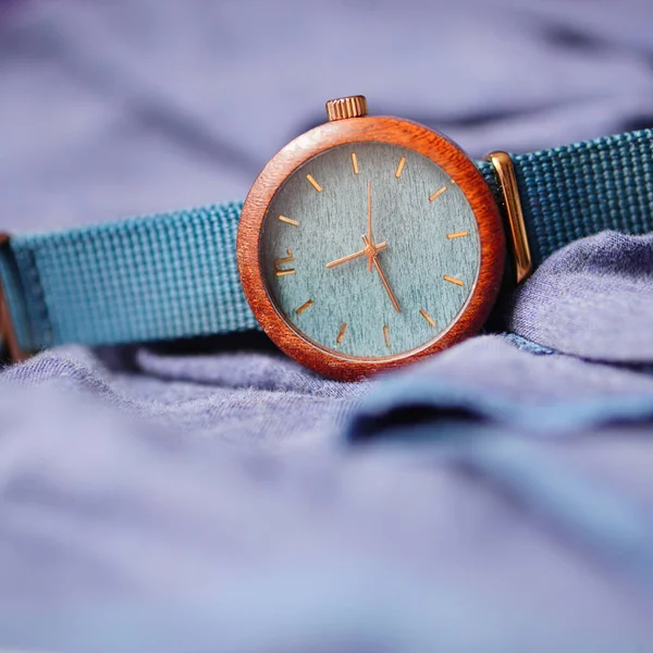 Zbliżenie Drewnianej Kobiety Zegarek Niebieskimi Paskami Fioletowej Tkaninie — Zdjęcie stockowe