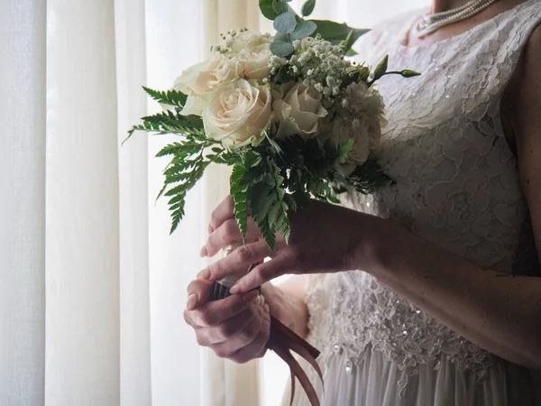 白いバラの花束でポーズをとってエレガントな白いウェディングドレスの女性 — ストック写真