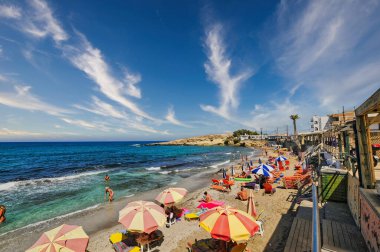 Hersonissos şehrinde bir plaj dolusu turist ve şemsiye.