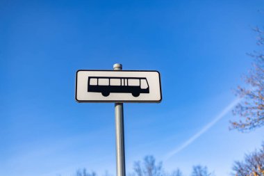 Arkadaki mavi gökyüzünde bir otobüs durağı tabelasına yakın çekim