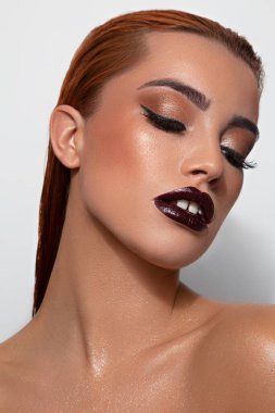 Beyaz bir arka planda profesyonel makyajlı ve saç stili olan çekici bir kadının portresi.