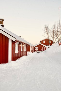Norveç 'in Lofoten Adası' ndaki karlı bir arazide kırmızı kulübelerin dikey görüntüsü.