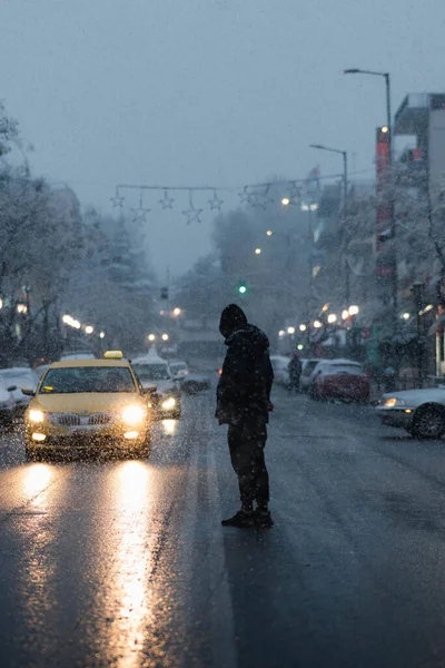雨と寒さの中 道路を横断するフード付きの男の垂直ショット — ストック写真