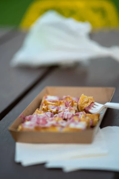 A vertical closeup of delicious waffles in a carton plate on a wooden bench on a blurred background