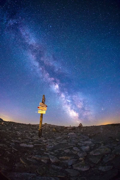 A vertical shot of rocky road with magic starry sky above it