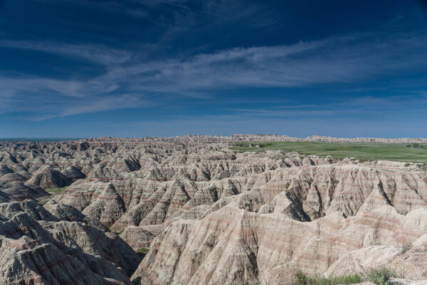 Colorful hills and rock formations on the background of green field, under a blue sky in Badlands National Park, South Dakota,USA