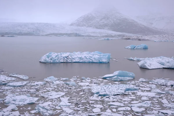 アイスランドのFjallsarlon氷河湖に浮かぶ大きな氷山 多くの小さな砕けた氷山に囲まれた大きな氷山 — ストック写真