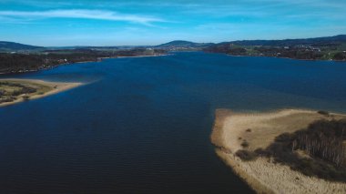 Dağların arkasındaki yeşil tarlalarla çevrili güzel bir deniz manzarası.