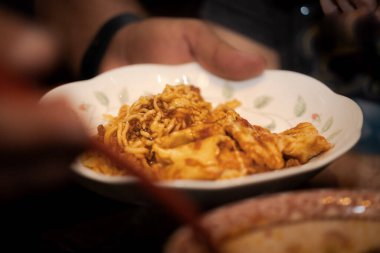 Aile yemeği sırasında elinde bir tabak spagetti tutan bir adam.