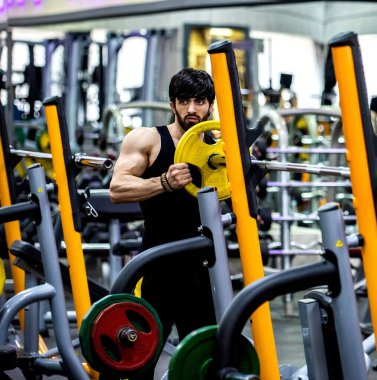 Formda, kaslı, beyaz bir adam spor salonunda çalışıyor.