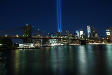 Brooklyn Köprüsü 'nün ve New York siluetinin gece manzarası. Körfezden iki çizgi neon ışığı.