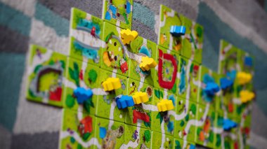 Mindok Carcassonne Junior masa oyununun kartlarından yapılmış bir haritanın üzerinde duran bir heykel.