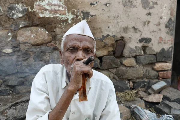 村中一位穿着西装革履的印度穷苦老人有选择地在屋外抽烟 也叫Beedi或Bidi或Cigarette — 图库照片