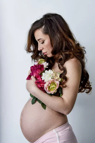 白い背景に花の花束を持つ妊婦の垂直ショット — ストック写真