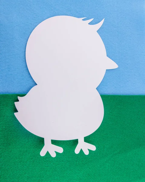 A white bird shape flat lay on a blue and green background