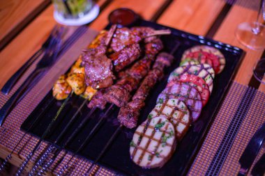 Izgara domates, patates ve soğanlı bir tabak tavuk ve biftek.