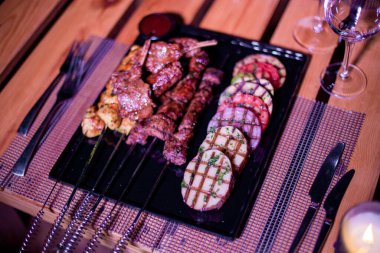 Izgara domates, patates ve soğanlı bir tabak tavuk ve biftek.