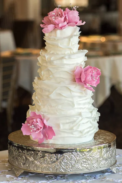 一个白色皱褶的结婚蛋糕 上面有可食用的花朵 — 图库照片