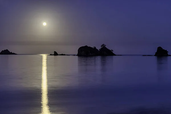 Full moon reflection in the still waters of Bland Bay, New Zealand