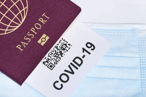 A closeup of a passport and a covid-19 test on a blue face mask