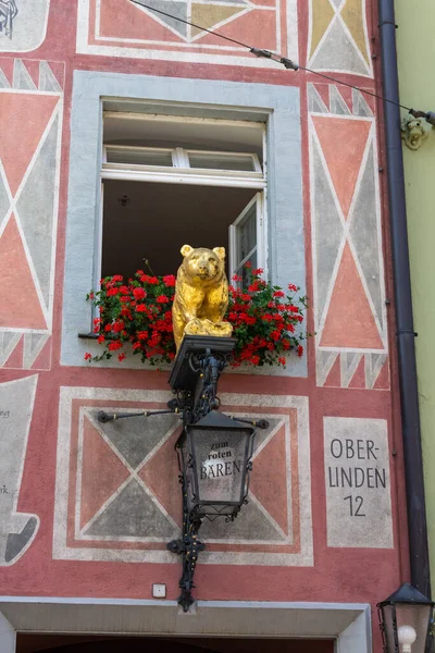 A vertical shot of a golden bear on top of a street lamp on a wall in downtown Freiburg, Germany