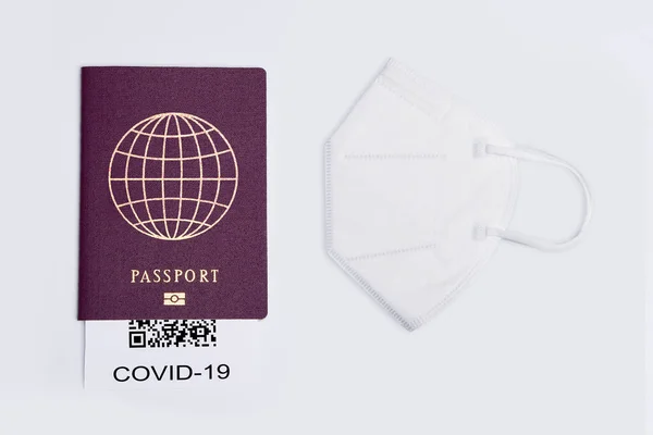 A closeup of a covid-19 test result, face mask and travel passport isolated on white background
