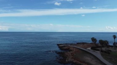 İspanya 'nın Mallorca şehrinde deniz suyu ve ufuk çizgisi üzerindeki yeşil bir sahil manzarası.