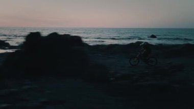Kayalık sahilde bisiklet süren bir adam