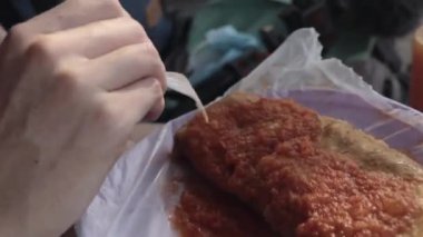 Meksika Playa del Carmen 'de beyaz plastik çatalla tamale kesen bir kadın el.
