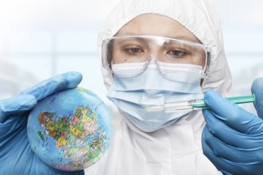 Bir doktor laboratuardaki Dünya gezegenine Coronavirus aşısı enjekte ediyor.