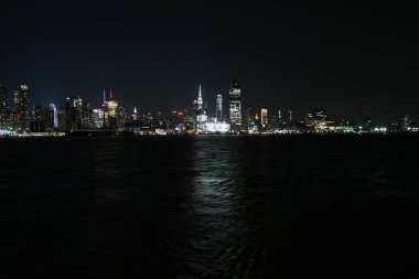 Büyüleyici New York şehri geceleri ışıklarla körfezden gökyüzüne yükseliyor.