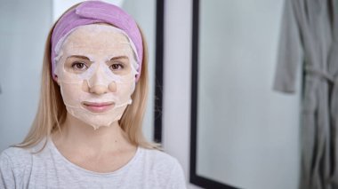 Yumuşak bir yüz maskesi takan beyaz bir kadın.