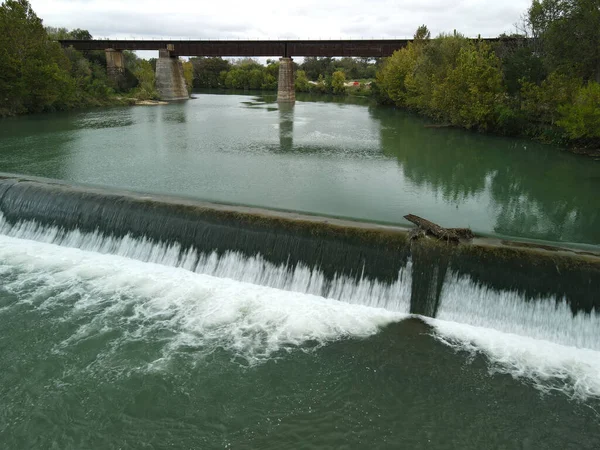緑に覆われた堤防を流れる川の上のダムの眺め — ストック写真