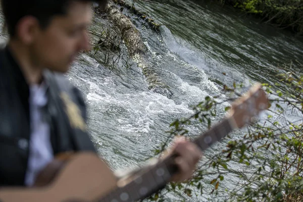 Homem Desfocado Tocando Guitarra Com Rio Fundo — Fotografia de Stock
