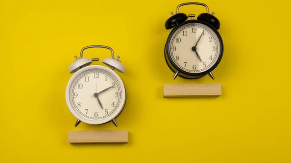 A copy space of a clock concept. Time Concept about the importance of time. Selective focus on a black and white alarm clock on a yellow background.