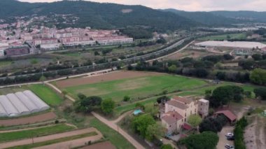 Arkasında binalar ve dağlar olan tarlaların havadan görünüşü