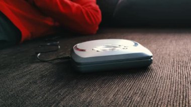 Evde müzik dinleyen kulaklıklı tanınmayan bir adam. Rahatlamış bir adam evdeki kanepede bir diskçiyle müzik dinliyor..