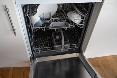 Birleşik Krallık enerji krizi ikilemini gösteren tabakları olan beyaz bir bulaşık makinesi. Elle mi yoksa makineyle mi yıkanmak daha ucuz?.