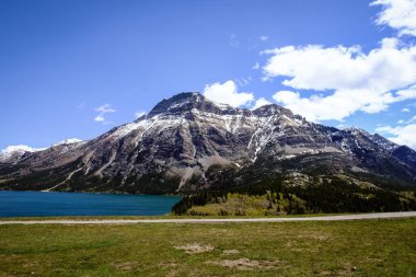 Karla kaplı dağların arkasındaki gölün yakınındaki yeşillik alanının havadan görünüşü