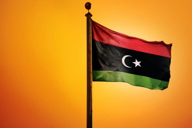 Libya 'nın ulusal bayrağı turuncu arka planda izole edilmiş bir bayrak direğinde
