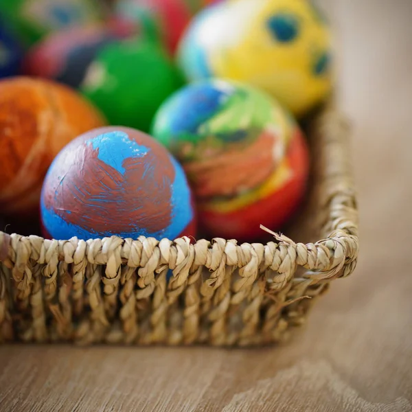 一张特写照片 是一张彩色彩绘的东方蛋 放在木制桌子上的稻草篮里 — 图库照片