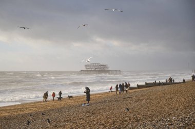 Gün batımında Brighton 'daki eski bir rıhtımda yaşayan insanlar.